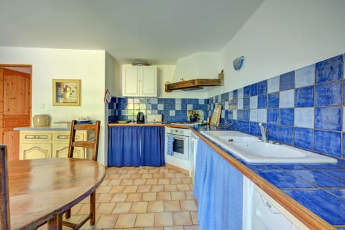 Cuisine du gîte Romarin au Domaine Bellavigne avec carrelage bleu et blanc, comptoirs en bois et coin repas