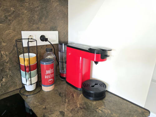 Red coffee machine and capsule holder on kitchen counter at Sylvie Conciergerie apartment in Rosas, Spain