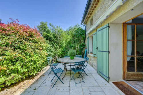 Terrasse avec assises bleues, table de patio et vue sur un jardin luxuriant au Domaine Bellavigne Gîte Romarin, Forcalquier
