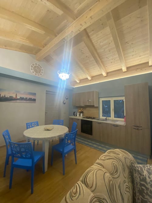 Moderna cucina open-plan e zona pranzo dell'appartamento Villa Maria a Roggiano Gravina con travi in legno