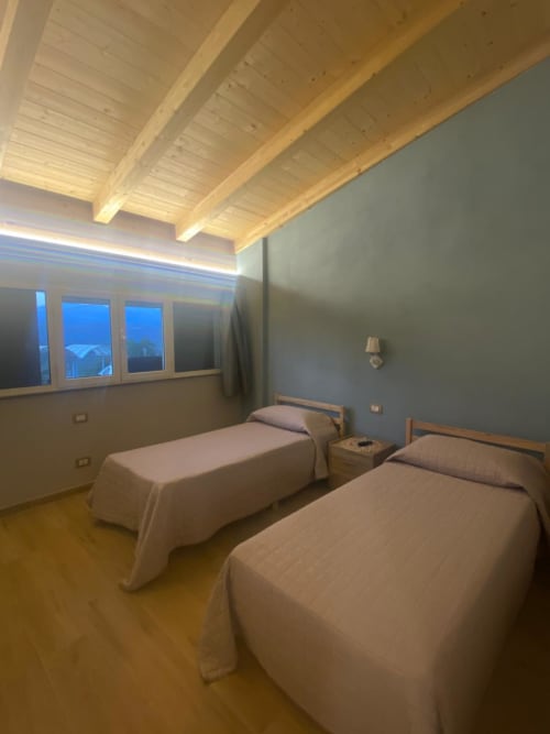 Camera doppia Villa Maria con travi in legno a vista, vista sulla campagna e illuminazione moderna a Roggiano Gravina
