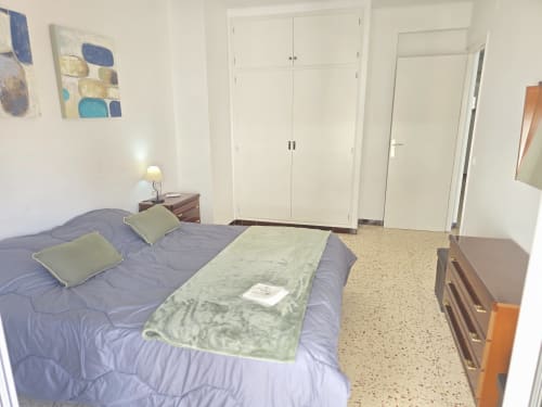 Spacious bedroom in family apartment in Rosas with double bed, wardrobe, and city views