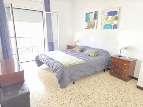 Spacious bedroom in Rosas apartment with double bed, balcony, modern furnishings and abstract artwork
