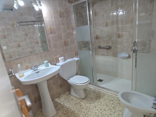 Modern bathroom with pedestal sink, toilet, bidet, and walk-in shower in Rosas apartment rental