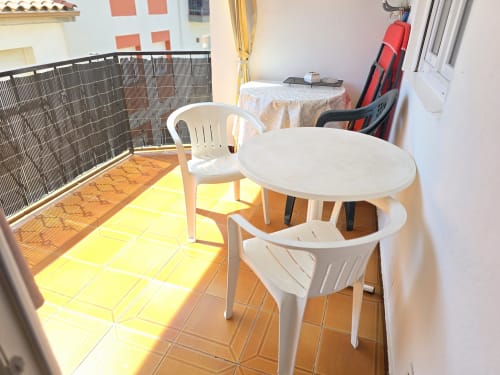 Sunny balcony with white furniture and table at Sylvie Conciergerie apartment in Rosas, Spain
