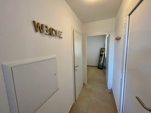 Bright hallway at Résidence Marina di Bravone apartment with white doors and Welcome sign in Linguizzetta