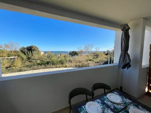 Balcony dining area at Marina di Bravone with sea view, Linguizzetta, overlooking beach and vegetation
