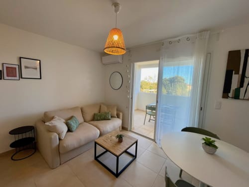 Modern T2 apartment at Marina di Bravone, Linguizzetta with beige sofa, wooden coffee table, and sea view balcony access