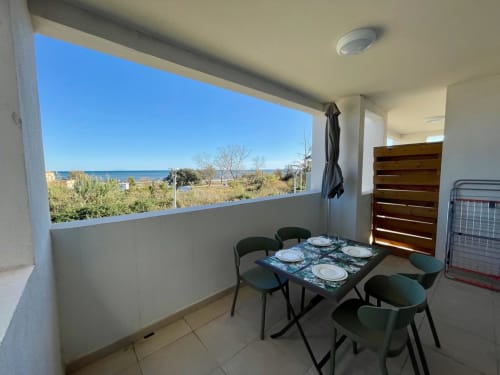 Beachfront apartment balcony at Résidence Marina di Bravone with dining table, sea views, and sandy beach access in