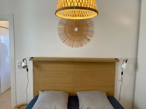 Modern hotel bedroom at Résidence Marina di Bravone with wooden headboard, pendant lamp, and nautical decor