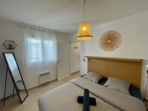 Modern bedroom at Résidence Marina di Bravone with wooden bed, pendant lamp, and sea view windows in Linguizzetta