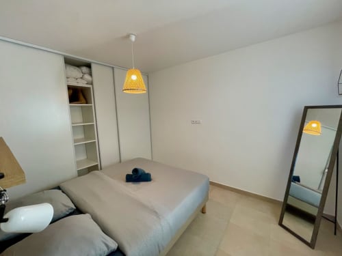 Modern bedroom at Résidence Marina di Bravone with bed, pendant lighting, storage, and floor mirror