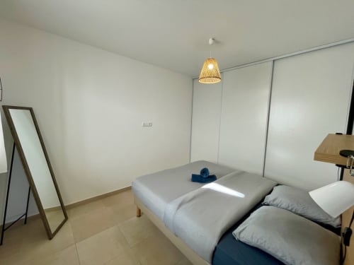 Camera moderna della Résidence Marina di Bravone a Linguizzetta con letto, specchio e lampada a sospensione intrecciata