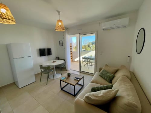 Moderno monolocale a Résidence Marina di Bravone con zona living, angolo cottura, divano beige e accesso a terrazza con vista mare
