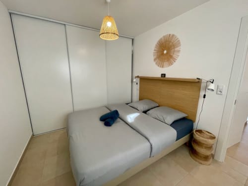 Camera moderna della Résidence Marina di Bravone con letto matrimoniale, testata in legno e arredamento minimalista a Linguizzetta