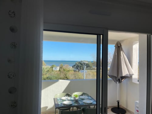 Balcone con vista mare a Marina di Bravone, Linguizzetta, con tavolo da pranzo, ombrellone e costa della Corsica