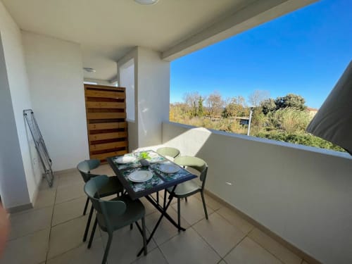 Zona pranzo in balcone presso Résidence Marina di Bravone con vista mare, tavolo e sedie con affaccio sul giardino