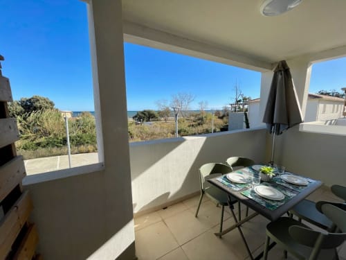 Balcone dell'appartamento fronte mare a Marina di Bravone con vista sul mare, tavolo da pranzo e paesaggio costiero a Linguizzetta