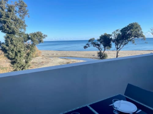 Beachfront view from Marina di Bravone apartment with sea, sandy beach, trees and toilet seat visible in Linguizzetta,