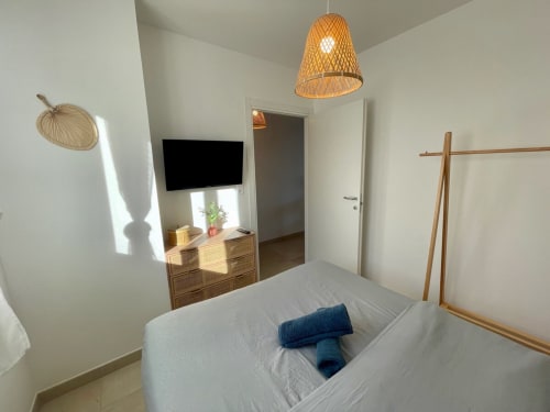 Modern bedroom at Résidence Marina di Bravone in Linguizzetta with woven pendant light, wooden furniture, and sea-view