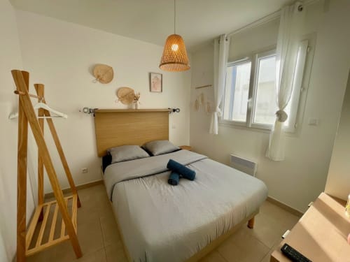 Bright modern bedroom at Résidence Marina di Bravone with wooden bed, woven pendant light, and glass doors in Linguizzetta,