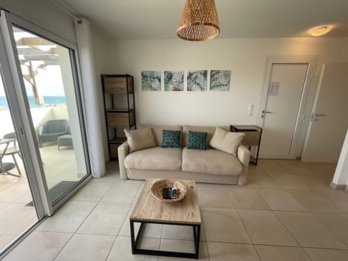 Monolocale fronte mare alla Résidence Marina di Bravone con divano color crema, tavolo in legno e accesso alla vista sul mare
