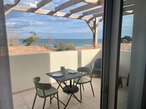 Terrazza fronte mare a Marina di Bravone con tavolo da pranzo, vista oceano e pergolato in legno sulla costa corsa