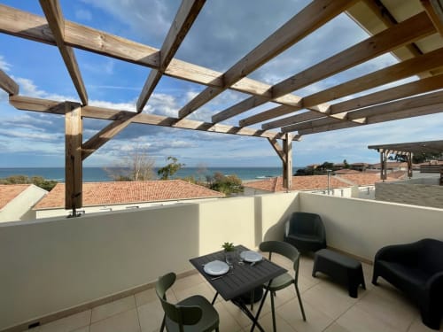 Terrazza fronte mare della Résidence Marina di Bravone con vista sul mare, pergolato in legno, zona pranzo e salotto