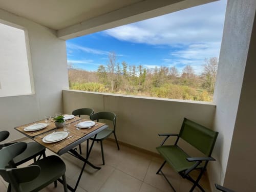 Balcony dining area at Marina di Bravone overlooking forest landscape with set table and chairs