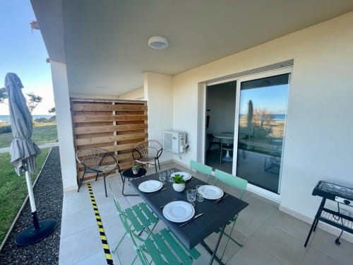 Marina di Bravone apartment patio with dining table, chairs, and ocean view in Linguizzetta