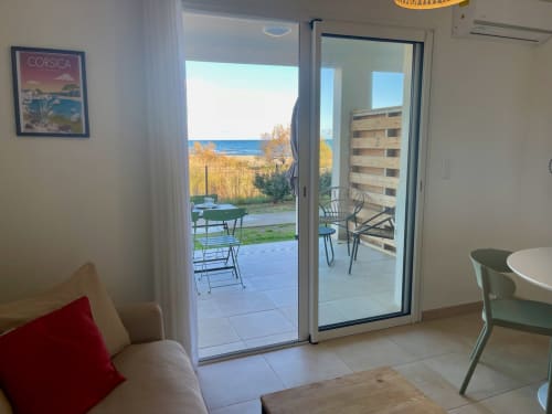 Bright apartment at Résidence Marina di Bravone in Corsica with ocean views through glass doors, patio seating, and modern