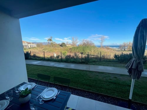 Marina di Bravone apartment terrace with dining table overlooking garden, pool, and Corsican coastline