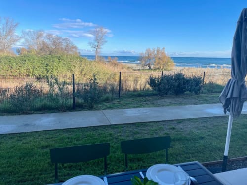 Beachfront terrace view at Résidence Marina di Bravone with ocean vista, dining setup, and coastal landscape in Linguizzetta