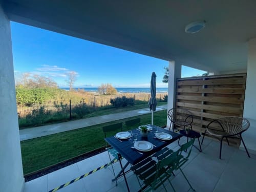 Beachfront terrace at Marina di Bravone apartment with dining setup and sea view in Linguizzetta, France