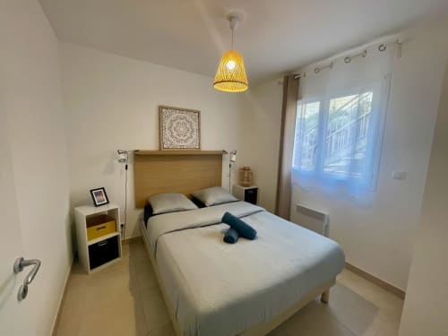 Modern bedroom at Résidence Marina di Bravone in Linguizzetta with wooden bed, yellow pendant light, and large windows