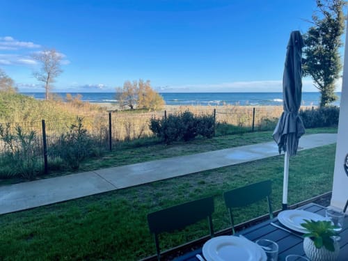Beachfront terrace at Résidence Marina di Bravone with sea view, dining setup, umbrella, and private beach access in