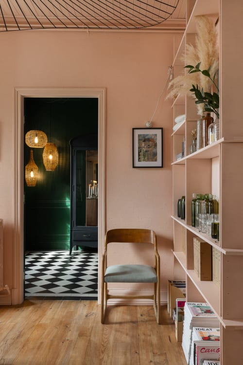 Salon pêche au Moulin Moulin BnB avec chaise en bois, étagères, tableaux encadrés et vue sur l'entrée vert foncé