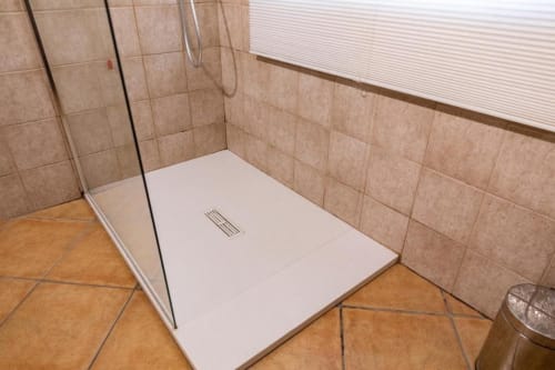 Modern white shower tray with glass partition in beige tiled bathroom at Mas Collection hotel in Bari, Italy