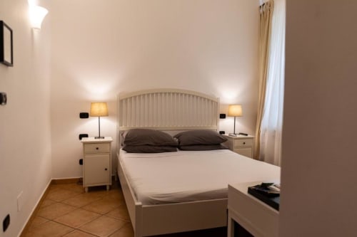Camera matrimoniale Deluxe di Mas Collection Bari con letto bianco, lampade notturne e tende con vista giardino