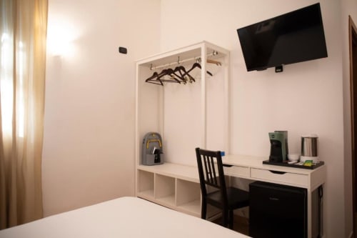 Camera moderna dell'hotel con scrivania, TV a schermo piatto, armadio e sedia nera presso Mas Collection a Bari
