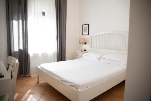 Camera luminosa con letto bianco e vista giardino nella Deluxe Room di Mas Collection Bari, dotata di servizi moderni