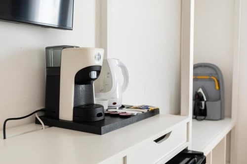 Macchina da caffè sulla scrivania della Mas Collection Deluxe Room a Bari, con TV e ripiani con servizi