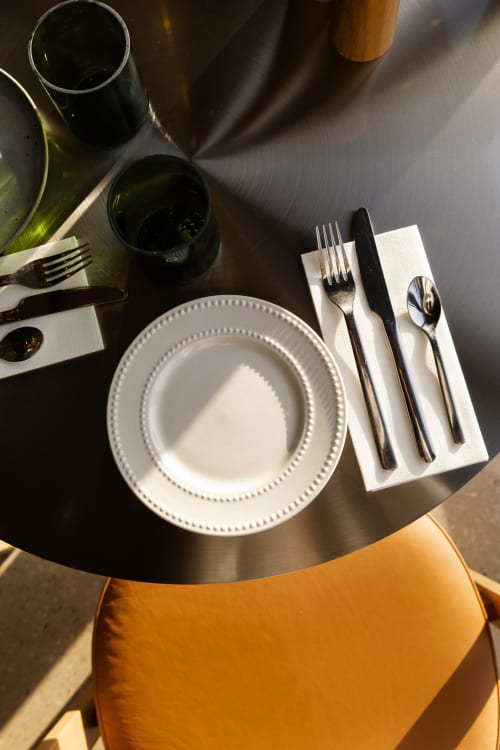 Mise de place élégante au Moulin Moulin avec assiettes à perles blanches, verres à vin et couverts de prestige sur table sombre