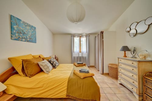 Chambre lumineuse aux draps jaunes au Domaine Bellavigne Gîtes, Forcalquier, avec mobilier en bois et vue sur le jardin