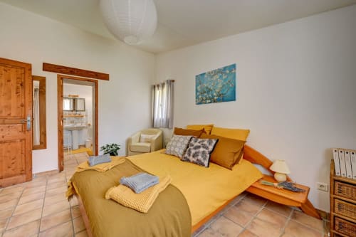 Chambre lumineuse du Gîte Agave à Domaine Bellavigne avec literie jaune, mobilier en bois et vue sur le jardin à Forcalquier