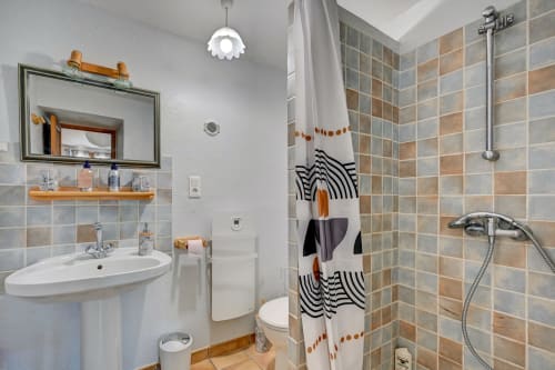 Salle de bain moderne du gîte Agave au Domaine Bellavigne avec douche carrelée, lavabo sur colonne et serviettes décoratives