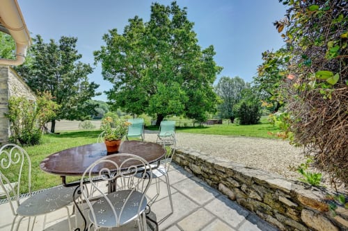 Terrasse avec mobilier en fer forgé surplombant les jardins paysagés du gîte Domaine Bellavigne à Forcalquier