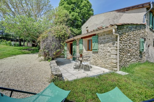 Maison en pierre avec volets verts et terrasse aménagée au Domaine Bellavigne Gîtes et Spa à Forcalquier, avec jardin et espace de détente