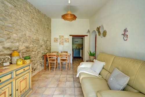 Séjour douillet à Domaine Bellavigne avec murs en pierre, canapé jaune, table à manger et décoration rustique