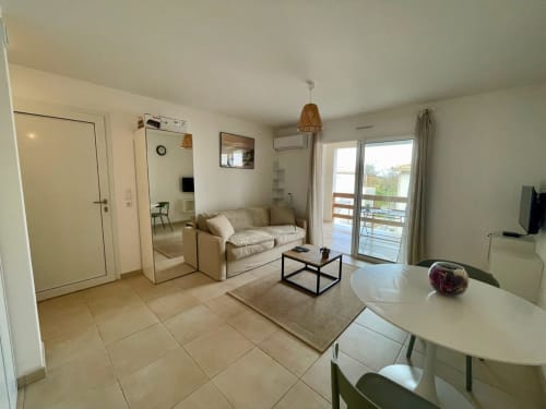Moderno monolocale a Résidence Marina di Bravone con divano beige, tavolo da pranzo e balcone con vista mare a Linguizzetta